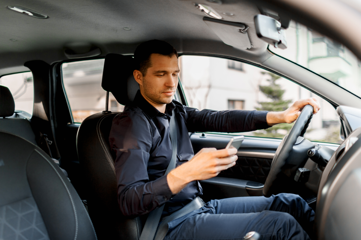 Distracted male driver looking at mobile phone